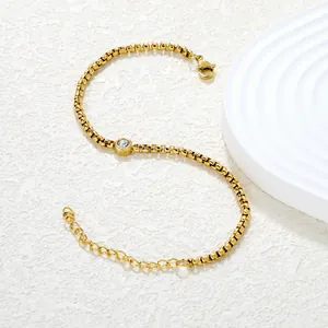 Dettaglio del bracciale a catena dorata con zircone rotondo e chiusura a moschettone