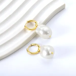Eleganti orecchini a cerchio dorati con grandi perle barocche bianche su vassoio
