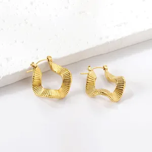 Elegante gouden onregelmatige geometrische oorringen met geribbelde textuur op witte steen