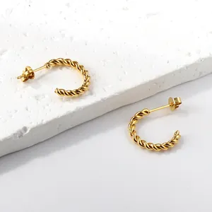 Elegante gouden gedraaide C-vormige oorringen op een minimalistische stenen display