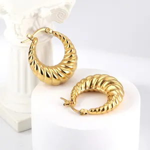 Elegante gouden gedraaide oorringen met croissant-ontwerp op witte sokkels