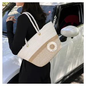 Detail of woven straw tote bag with rope handle and daisy flower on white car background