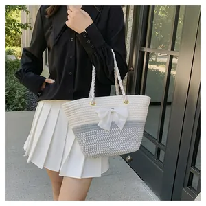 Detail of woven tote bag featuring a white ribbon bow and two-tone woven texture design