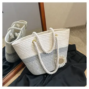 Detail of woven tote bag with sunflower charm and blue-white braided rope texture