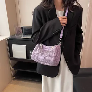 Purple pleated cloud shoulder bag with pearl chain and fashion label on black suit outfit