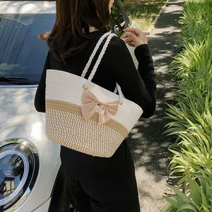 Two-tone woven straw tote bag with large pink satin bow and white rope handles