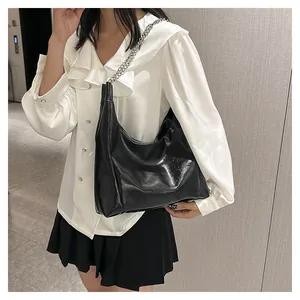 Détail du sac hobo noir brillant avec une bandoulière en chaîne en métal argenté poli