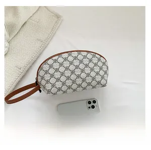 Dettaglio della pochette grigia a quadrifogli con manico marrone rispetto a un telefono