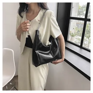 Détail du sac hobo noir minimaliste avec bandoulière en chaîne et texture plissée élégante