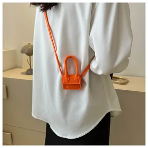 Bright orange micro crossbody bag with oversized handle on white shirt background