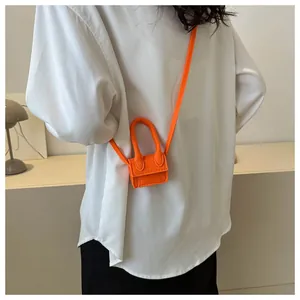 Detail of an orange felt micro mini bag worn as a crossbody fashion accessory