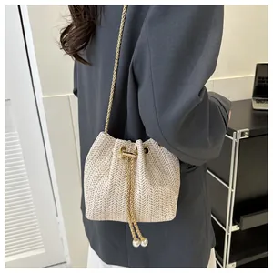 Detail of woven straw bucket bag with gold chain and large pearl drawstring accents