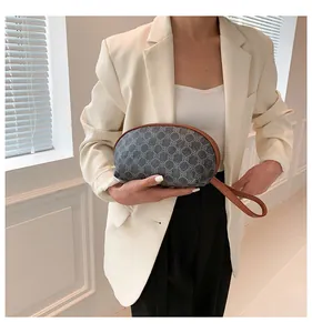 Dettaglio pochette con motivo geometrico e cinturino marrone su blazer beige
