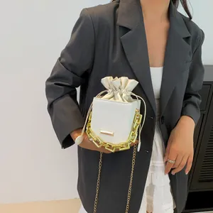 White bucket bag with lychee grain leather, gold chain strap, and drawstring inner bag