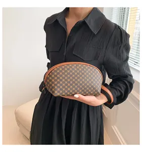 Dettaglio di una pochette con motivo geometrico e cinturino in pelle tenuta da una modella