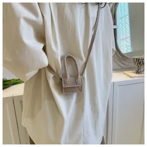 Detailed view of a micro beige crossbody bag with a large circular handle on a model