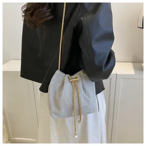Detail of silver bucket bag with gold chain strap and pearl accents on a model
