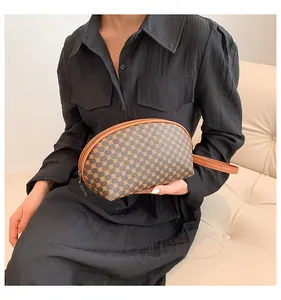 Dettaglio di una borsa marrone a forma di conchiglia con motivi geometrici e cinturino