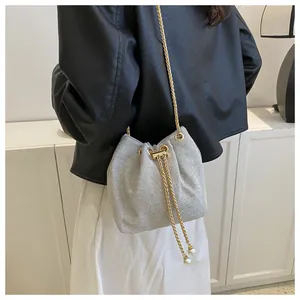 Detail of silver mesh bucket bag featuring gold chain strap and pearl drawstring tassels