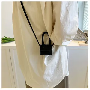 Detail of a mini black lipstick crossbody bag showing its compact size and matte texture