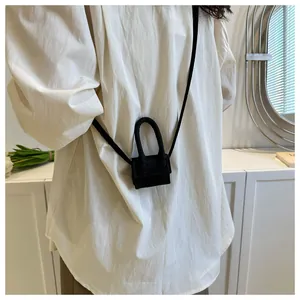Close-up of a micro black crossbody bag charm worn with a stylish white shirt