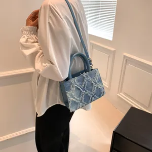 Blue denim crossbody bag with white star fringe patterns and gold hardware