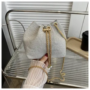 Detail of white mesh bucket bag featuring gold chain strap and elegant pearl accents