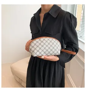 Dettaglio di una borsa a mano semicircolare con motivi geometrici e cinturino in pelle