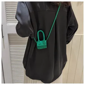 Detailed back view of a mini green crossbody bag styled with a black silk shirt
