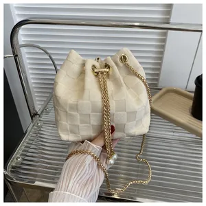 Detailed shot of cream bucket bag featuring checkered knit texture and pearl drawstrings