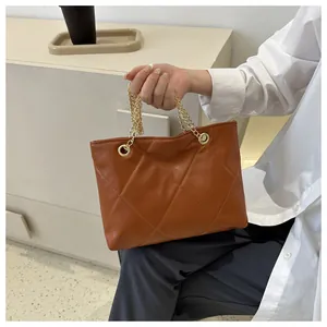 Détail d'un sac cabas marron matelassé avec une poignée en chaîne métallique dorée