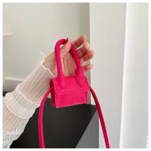 Detail of rose pink mini felt handbag with top handle and crossbody strap closeup