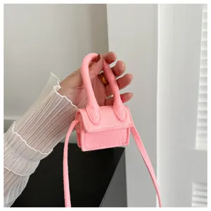 Mini pink felt crossbody bag held in hand showing compact size and soft wool texture