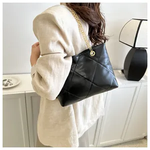 Détail du sac cabas matelassé noir avec bandoulière en chaîne dorée porté par un modèle