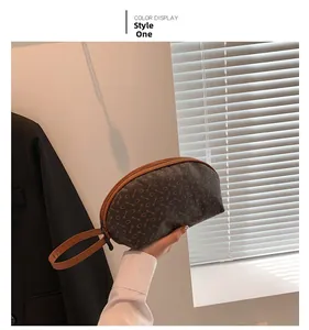 Primo piano di una borsa a mano marrone scuro a semicerchio con eleganti stampe a ferro