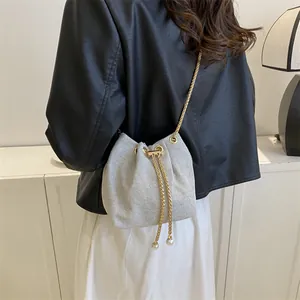 Chic silver bucket bag with pearl charms and gold chain strap shown on a model