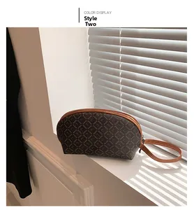 Dettaglio di una borsa a mano semicircolare marrone scuro con cinturino in pelle