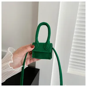 Detailed close-up of a mini green felt lipstick bag with a top handle and slim strap