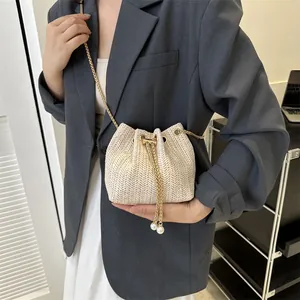 Minimalist beige woven bucket bag with gold chain strap and pearl drawstring details