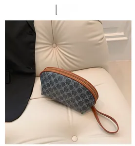 Dettaglio di una pochette floreale semicircolare con finiture in pelle marrone su un divano