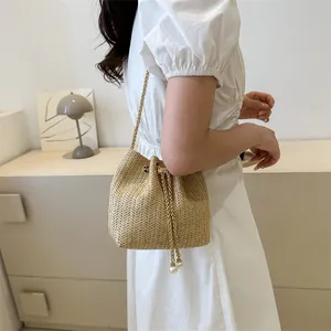 Chic woven bucket bag with gold chain strap and pearl drawstring in a lifestyle setting
