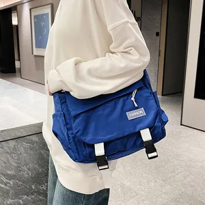 Grand sac à bandoulière bleu de style japonais porté par un mannequin dans un couloir moderne