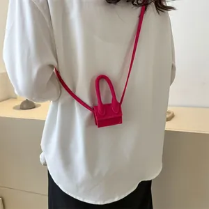 Magenta minimalist micro crossbody bag with single handle worn by a model in white