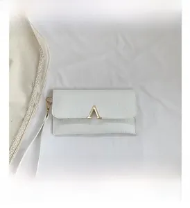 Close-up of white crocodile pattern clutch bag with gold V-shaped metal hardware detail