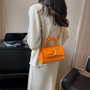 Bright orange crocodile embossed leather handbag with golden buckle and crossbody strap