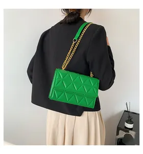 Detail der grünen Stepptasche mit goldenem Kettenriemen an der Modellschulter