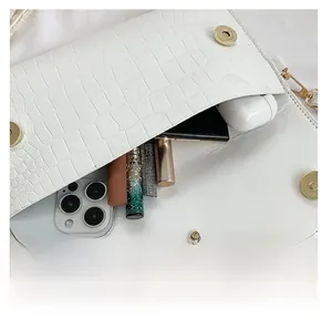 White faux crocodile leather envelope bag showing interior capacity for phone and makeup