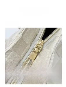 Gros plan détaillé de la fermeture éclair dorée sur le sac cabas tissé beige à carreaux