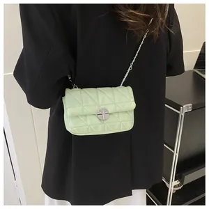 Gros plan d'un sac bandoulière matelassé vert clair avec un fermoir tournant argenté