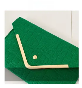 Detail of green crocodile-textured envelope clutch with V-shaped gold metal trim